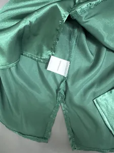 Gros plan détaillé du tissu satin vert avec étiquette d'entretien 100% polyester