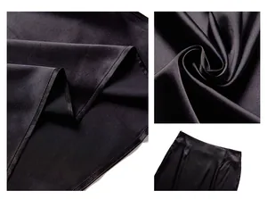 Detailed macro view showing the smooth texture and fine stitching of a black satin midi skirt