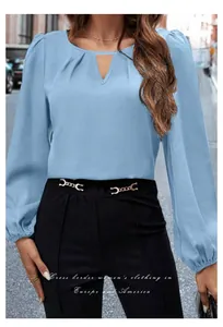 Detalle de blusa de satén azul claro con abertura en V y elegantes mangas abullonadas