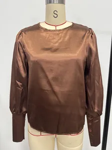 Detalle de una blusa de satén marrón con mangas abullonadas y puños con botones