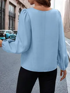 Blusa de satén azul claro con mangas abullonadas vista desde la parte trasera.