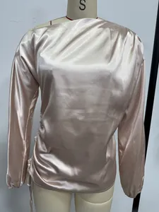 Close-up of elegant champagne satin blouse featuring an asymmetrical neckline.