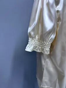 Detailed close-up showing the ruffled smocked cuff on a cream satin short sleeve shirt