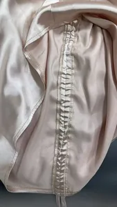 Macro close-up view of the fine stitching and ruched fabric details on a satin blouse