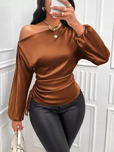 Close-up of brown satin asymmetrical one-shoulder long sleeve blouse with side ruching.