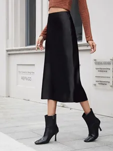 Mannequin portant une jupe midi en satin noir à taille haute dans une rue urbaine.
