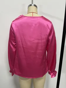 Back view of a vibrant hot pink satin long-sleeve blouse featuring elegant ruffled cuffs