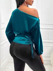Close-up detail of a teal blue satin one-shoulder blouse with ruched sleeves and tie