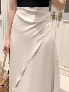 Close-up of elegant cream satin midi skirt with draped wrap detail and silky texture