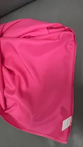 Macro view of hot pink satin shirt fabric showing 100% polyester label