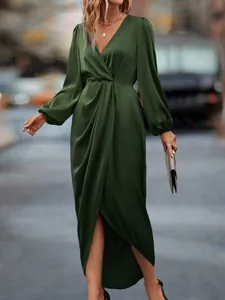 Close-up of the pleated wrap waist and lantern sleeves on a luxurious dark green satin dress