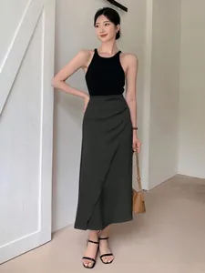 Full-length view of an Asian model wearing a charcoal satin midi skirt and black top.