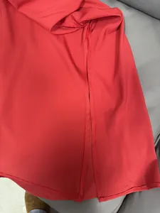 Detalle de un vestido de satén rojo con abertura lateral alta y costura de dobladillo
