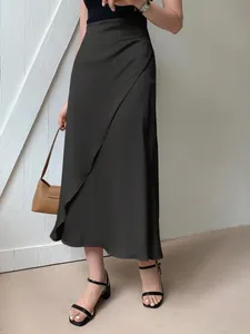 Elegant black satin midi skirt featuring a wrap design and smooth silk-like texture detail