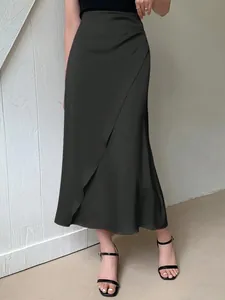 Detail shot of a black satin midi skirt featuring a high waist and elegant wrap design.