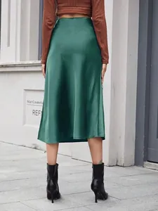Vue arrière d'une jupe midi en satin vert à taille haute avec un drapé élégant.