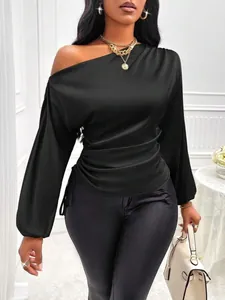 Detailed close-up of a black asymmetrical satin blouse with elegant gathered waist