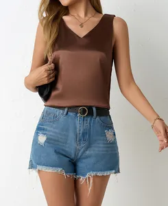 Detail view of a glossy brown satin V-neck tank top styled with denim shorts and a belt