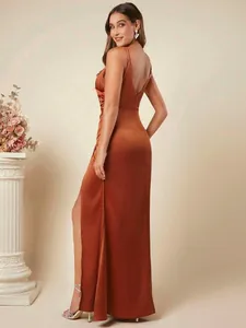 Elegante roestkleurige satijnen maxi-jurk met plooien en zijsplit gezien vanaf de achterkant.