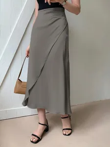 Detail view of a grey satin midi skirt with an elegant wrap-style front overlap design