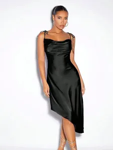 Détail d'une robe nuisette élégante en satin noir avec un ourlet asymétrique.