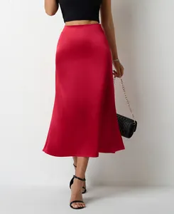 Gros plan d'une élégante jupe midi en satin rouge avec ourlet sirène et taille haute.