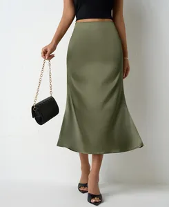 Jupe midi élégante en satin vert olive avec un sac à main noir matelassé