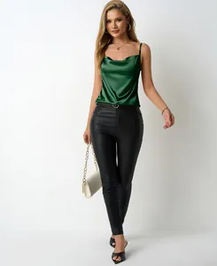 Elegant dark green satin cowl neck camisole top paired with black slim faux leather pants.