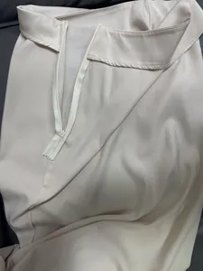Close-up detail of side zipper and smooth satin fabric texture on a cream midi skirt