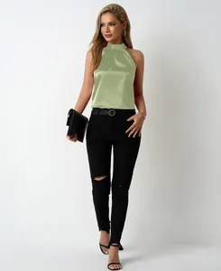 Detail view of a sage green satin halter neck blouse styled with chic black jeans.