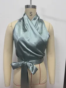 Detailopname van sage groene satijnen halter wikkelstop met elegant strikdetail in de taille.