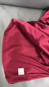 Detail view showing the burgundy satin blouse fabric and 100% polyester care label.