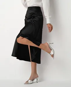 Close-up of elegant black satin midi skirt with high side slit and ruched detail