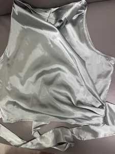Detailopname van de gladde satijnen stof van een lichtblauwe halter wrap top met strik