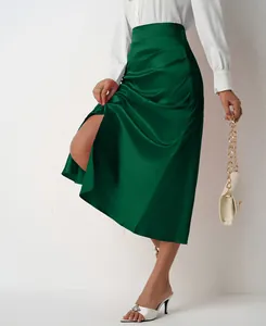 Detail of elegant green high waist satin midi skirt with side split and ruched accents.