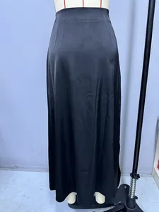 Detailed view of an elegant black satin maxi skirt with a side slit and silky finish