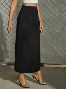 Elegant high-waisted black satin midi skirt shown on model against an industrial background