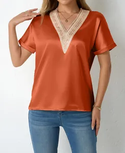 Detail view of elegant lace trim and satin fabric on the orange V-neck loose top
