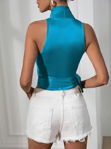 Gedetailleerd achteraanzicht van een blauwgroene satijnen haltertop met strik aan de zijkant.