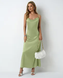 Modèle portant une robe midi en satin vert sauge à fines bretelles et sac blanc