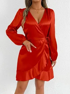Close-up of elegant orange satin long-sleeve wrap dress with ruffle hem detail