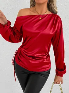 Close-up detail of smooth red satin fabric and side drawstring on elegant blouse