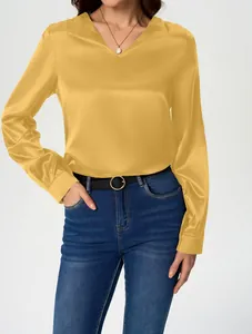 Detail view of a yellow satin long-sleeve blouse with V-neck and silky texture.