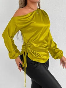 Close-up detail of women's mustard yellow satin one-shoulder long sleeve blouse with side drawstring