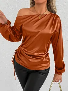 Detail view of burnt orange satin long sleeve blouse with asymmetrical shoulder
