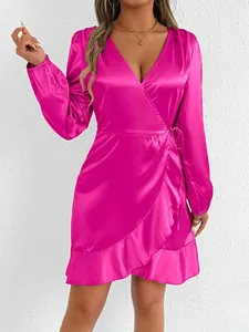 Detail of a bright pink satin long-sleeved wrap dress featuring a silk-like texture and ruffles