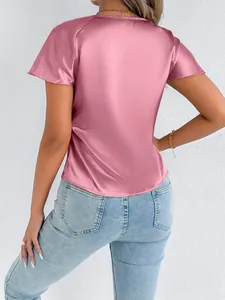 Back view of a shimmering pink satin short-sleeve blouse paired with light blue jeans.