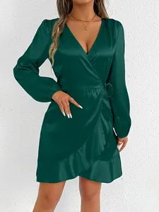 Detailed macro view of a deep green satin long sleeve wrap dress with elegant ruffle hem