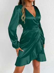 Detailed shot of an emerald green satin long sleeve wrap dress with elegant ruffle hem