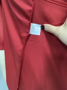 Detailed macro shot showing 90% polyester 10% elastane wash tag on red satin dress